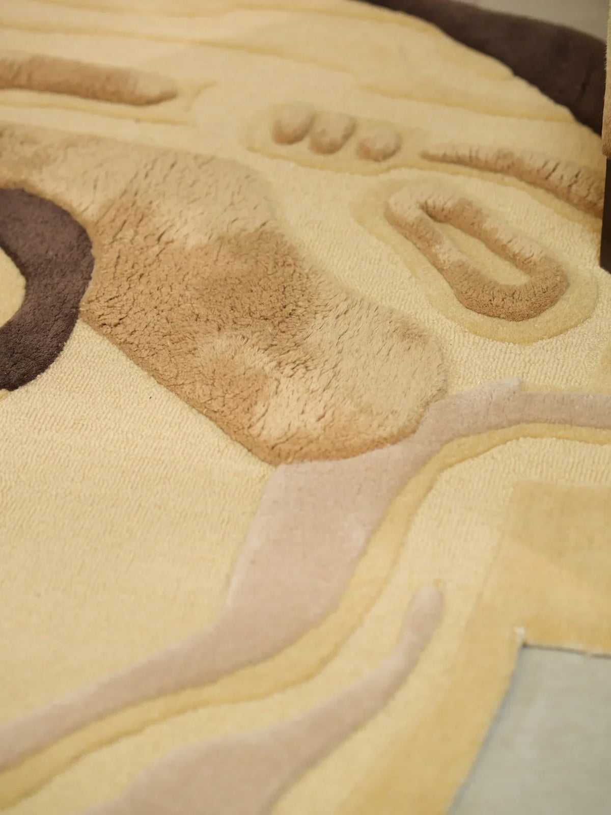Detailed view of beige and brown hand-tufted wool rug with raised textured pattern