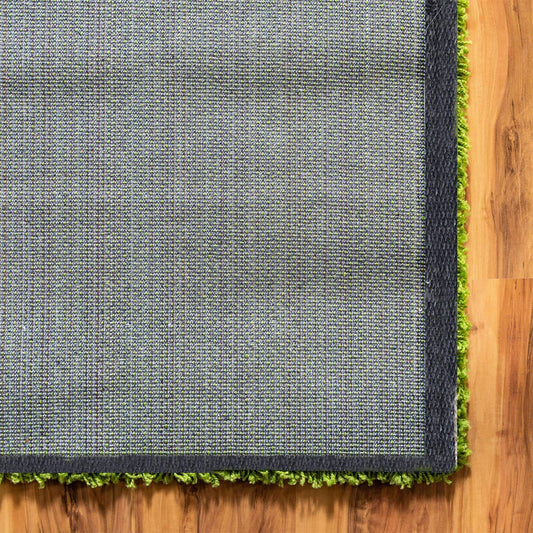 Green shaggy carpet showing rectangular shape, dark border and woven backing