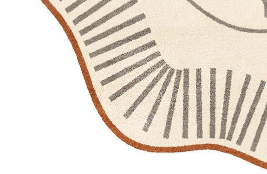 Ivory and rust rug close-up showing abstract face line art and grey radiating pattern