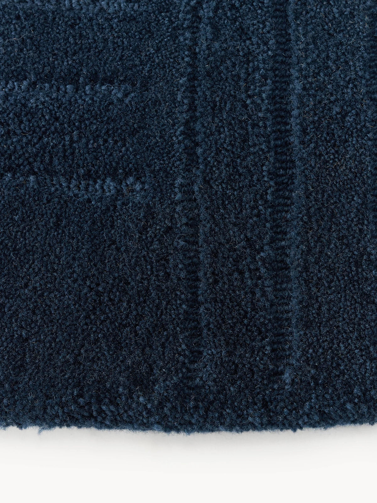 Navy circle rug close-up showing dark blue textured surface and linear pattern