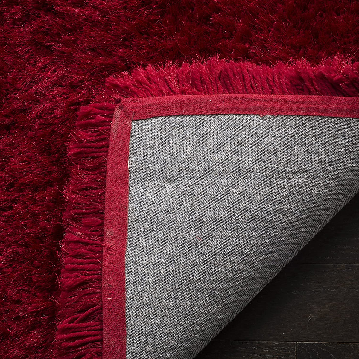 Red carpet showing shaggy deep red surface and carpet backing detail